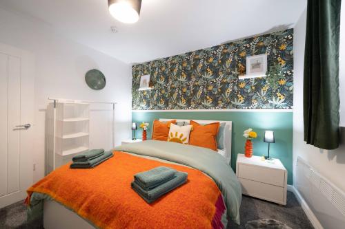 ein Schlafzimmer mit einem Bett mit einer orangefarbenen Decke in der Unterkunft Cosy City Stay - Heart of Cardiff in Cardiff