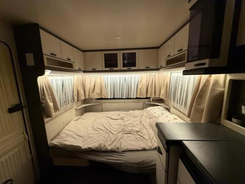 una pequeña cama en la parte trasera de una casa rodante en Fully Equipped Caravan 1, en Gentofte