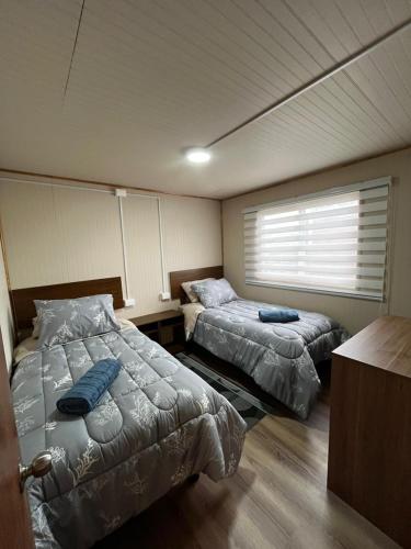 um quarto com duas camas e uma janela em Cabaña Puerta a la Patagonia em Chaitén