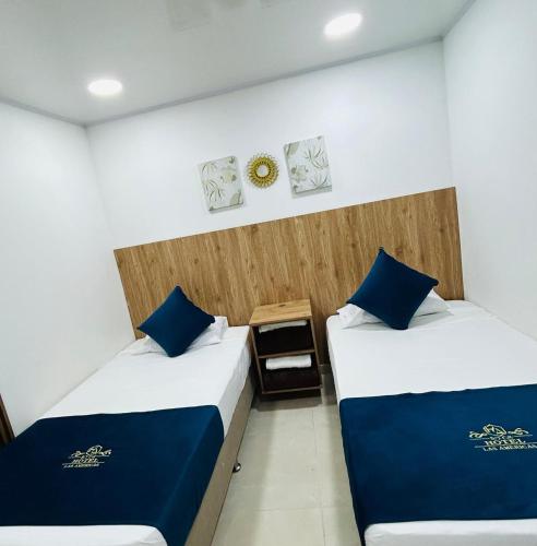 Dos camas en una habitación con almohadas azules. en Hotel Las Americas Confort, en Estación El Salto