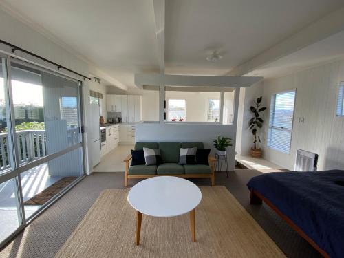 a room with a bed and a couch and a table at Treetop studio apartment in Hamilton