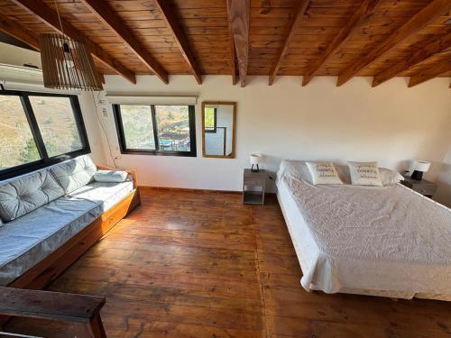 een woonkamer met een bed en een bank bij La Colina de Villa Yacanto in Villa Yacanto