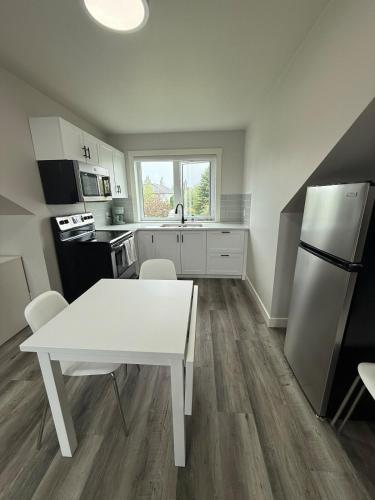 a kitchen with a white table and a refrigerator at Modern brand new loft suite! in Red Deer