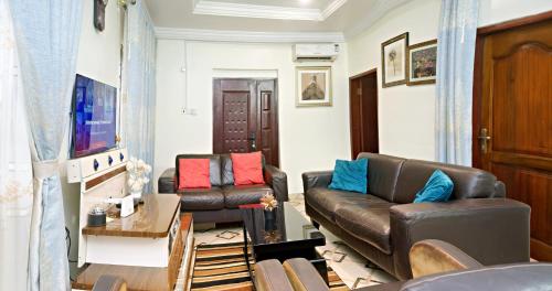 een woonkamer met 2 leren banken en een tv bij Two Bedrooms Standby Generator DSTV Netflix W-iFi in Takoradi