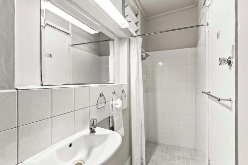 a white bathroom with a sink and a mirror at Arkana Motel in Maryborough