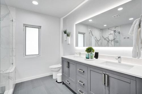 een badkamer met een wastafel, een toilet en een spiegel bij Cypress Breeze, Coastal Comfort! Heated Pool! in Pompano Beach