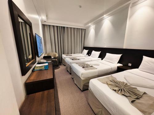 a hotel room with three beds and a table at Cent Al Azizia Hotel Makkah in Mecca