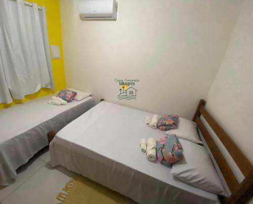 two beds in a small room with yellow walls at Casa Amarela Milagres in São Miguel dos Milagres