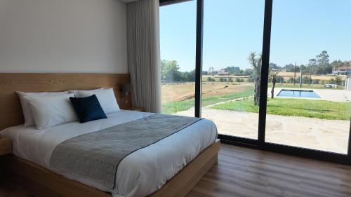 a bedroom with a bed and a large window at Casa Memórias da Lucinda in São Gens