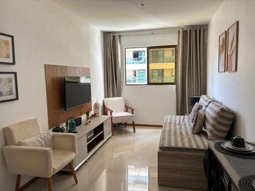 uma sala de estar com um sofá e uma TV em Costa Nova VIP - Flat moderno e aconchegante em Ponta Verde em Maceió
