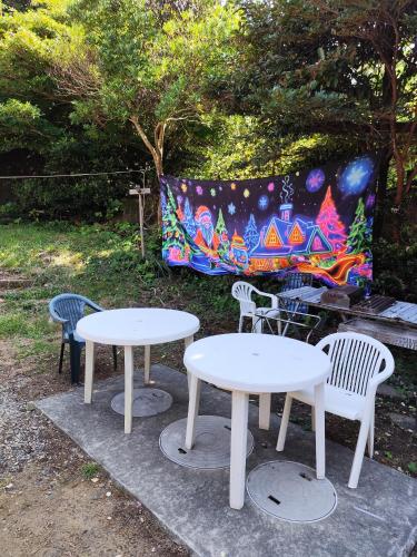 two white tables and chairs in front of a painting at 椿リゾートみさき in Shirahama