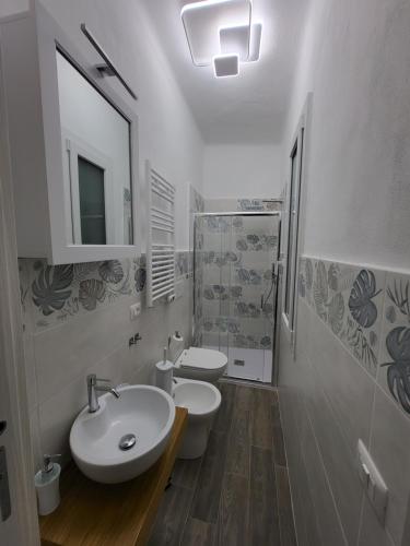 a white bathroom with two toilets and a sink at Casa Mafalda in Campiglia