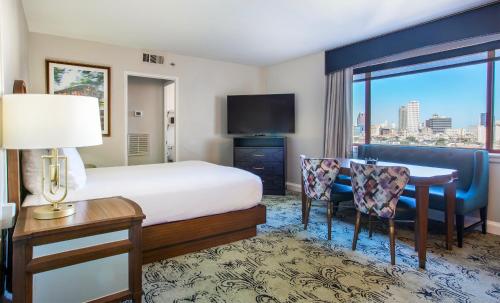 a hotel room with a bed and a desk and a television at Club Wyndham Avenue Plaza in New Orleans