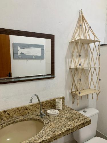 a bathroom with a sink and a mirror and a toilet at Suítes Cabanas Coral in Serra