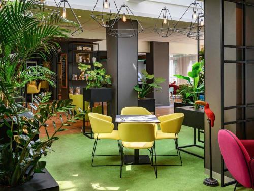 una habitación con plantas, mesa y sillas en Hotel Novotel Evry Courcouronnes, en Courcouronnes