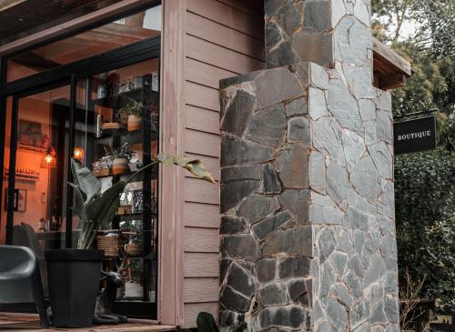 a building with a stone wall next to a store at Bella Bungalows in Punta Del Diablo