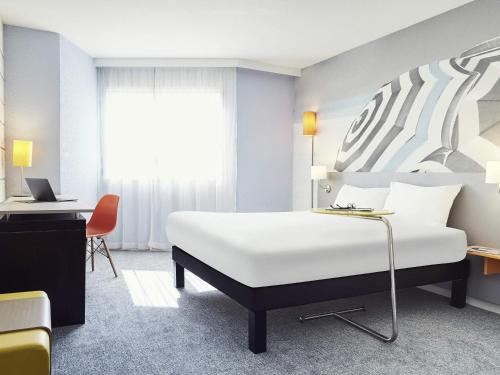 a hotel room with a white bed and a desk at Ibis styles Toulon la Seyne sur Mer in La Seyne-sur-Mer