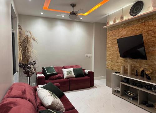 a living room with a red couch and a flat screen tv at Lar dos Fernandes in Belém