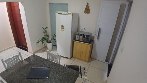 a kitchen with a table and a refrigerator at Quarto Solteiro sem TV in Artur Nogueira