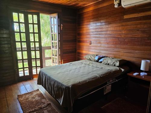 Schlafzimmer mit einem Bett mit Holzwänden und Fenstern in der Unterkunft Recanto Don Ciro in Uruguaiana