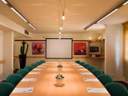 a conference room with a long table and green chairs at ibis Metz Centre Cathedrale in Metz