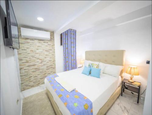 Un dormitorio con una cama blanca y un televisor. en 2 Guests 1bed Studio 3min To Beach And Main Street, en Sosúa