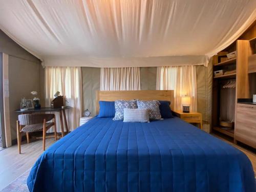 a bedroom with a blue bed and a desk at Premium Lakefront Cabin 4 The Cardinal in Bastrop