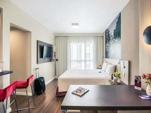 Cette grande chambre comprend un lit et une table. dans l'établissement Mercure Sao Paulo Alamedas, à São Paulo