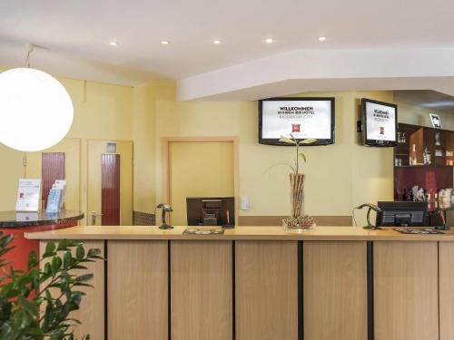 a waiting room with a counter with a flower on it at ibis Paderborn City in Paderborn