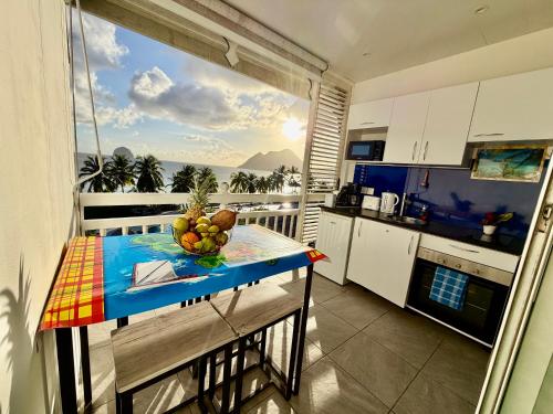 a kitchen with a table with a bowl of fruit on it at Studio Ti Saphir in Le Diamant