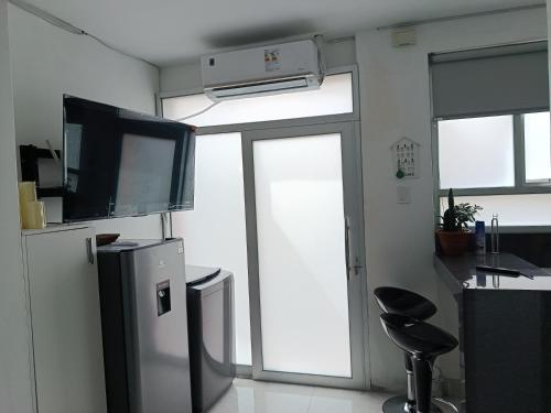a kitchen with a refrigerator and a counter with a stool at Estancia Acogedora en Tacna in Tacna