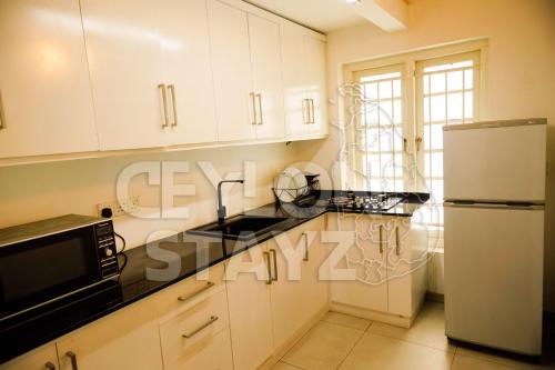 a kitchen with white cabinets and a black counter top at CEYLON STAYZ in Colombo