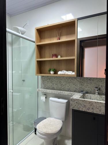 a bathroom with a toilet and a glass shower at Casa em Içara Prox Criciúma in Içara