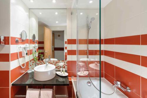 a bathroom with two sinks and a glass shower at Mercure München City Schwabing in Munich