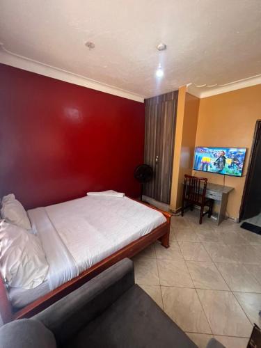 a bedroom with a large bed with a red wall at Bukoto pal in Kampala
