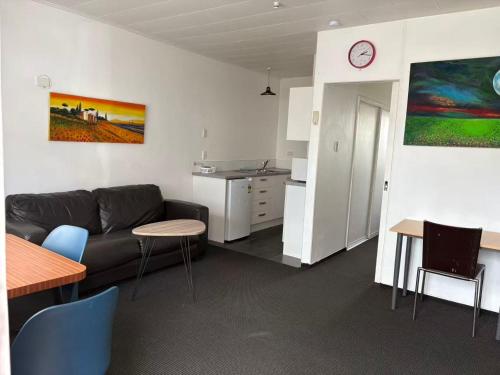 a living room with a couch and a table and a kitchen at Achilles Motel in Christchurch