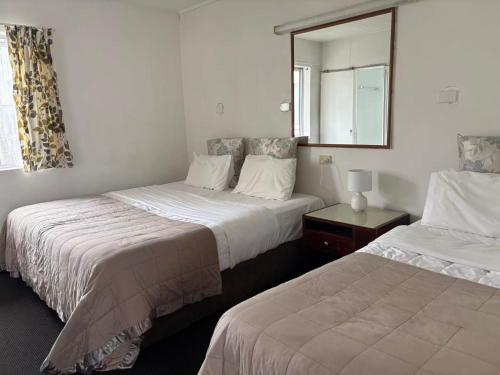 two beds in a hotel room with a mirror at Achilles Motel in Christchurch