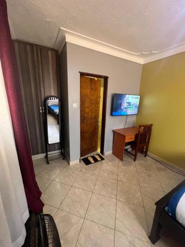 a room with a bedroom with a desk and a door at Lark suites -Bukoto in Kampala
