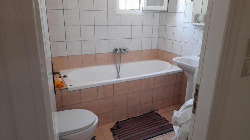 a bathroom with a tub and a toilet and a sink at Detached Vacation House with sea views at Chalikounas in Halikounas