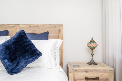 un lit avec un oreiller bleu et une lampe sur une table de nuit dans l'établissement Spacious Coastal Oasis - Ideal for Groups & Families, 
