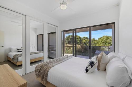 ウールグールガにあるZiggy's Beach House - Ocean views, Jacuzzi, Sauna!の大きなベッドと大きな窓のある寝室