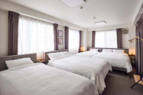 東京にあるとまりーとStay 西五反田のベッド4台と窓が備わるホテルルームです。