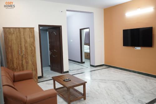 ein Wohnzimmer mit einem Sofa und einem Fernseher an der Wand in der Unterkunft Cozy Homes, Tiruvannamalai in Tiruvannāmalai