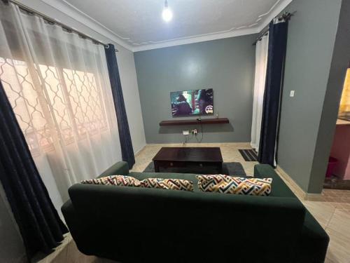 a living room with a couch and a tv at Cozy suites 3 in Kampala