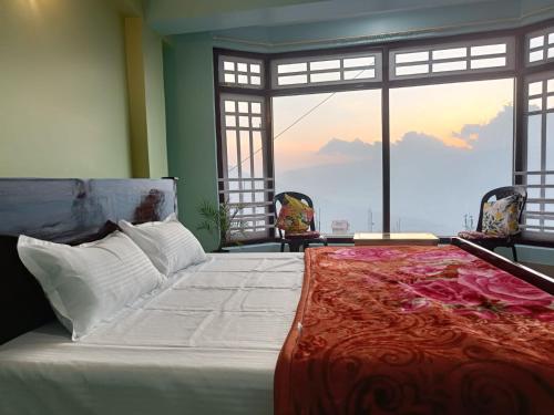 a bedroom with a large bed with a large window at The Mountain Range Homestay in Darjeeling