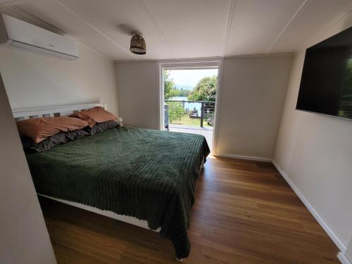 a bedroom with a bed and a large window at Tweed River Waterfront Cottage in Murwillumbah
