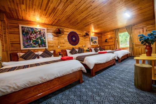a row of four beds in a room with wooden walls at Homestay Quản Thanh in Loung Co