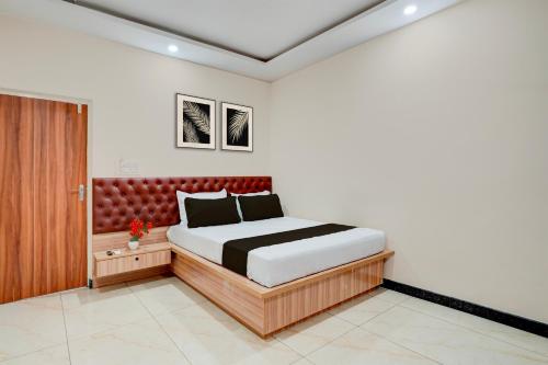 a bedroom with a bed with a red headboard at Super Hotel O Kachohalli Gate Formerly SRS Lodge in Tāvarikere