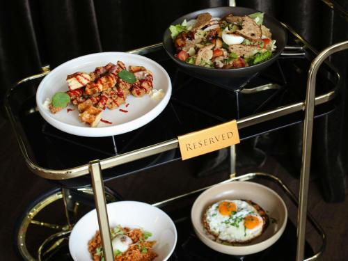 a display case with plates of food on a shelf at Mövenpick Hotel Auckland in Auckland