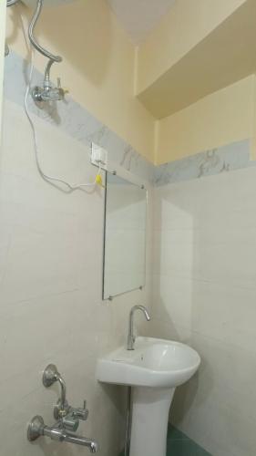 a white bathroom with a sink and a mirror at The Mountain Range Homestay in Darjeeling
